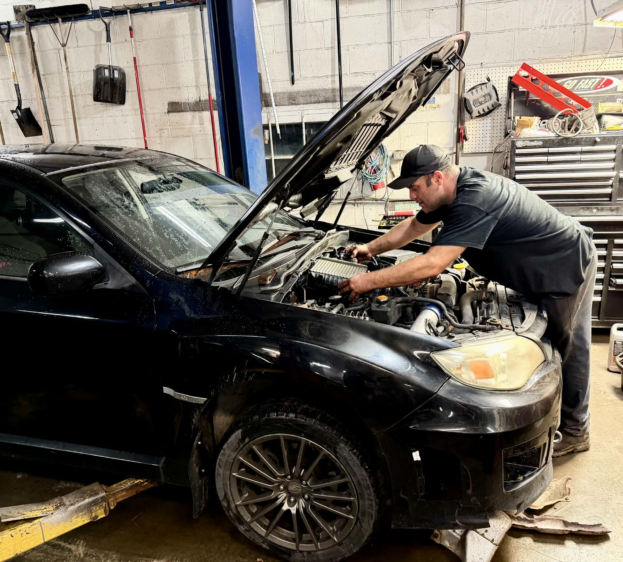 Mécanicien intervenant sous le capot d’un véhicule dans l’atelier Mongarage RN